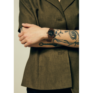 Nixon watch with bronze case and bracelet and black dial.